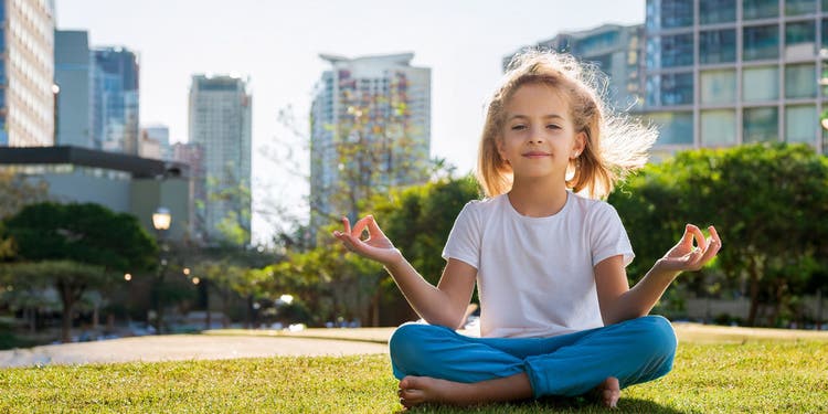 photo of a child meditating in a ciy park