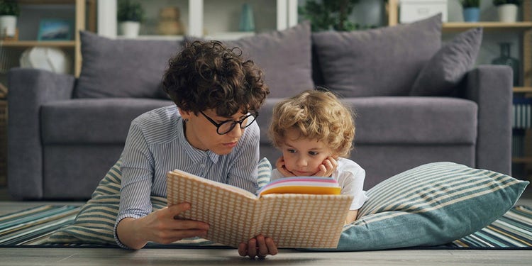 photo of mother and child laying on floor reading a book