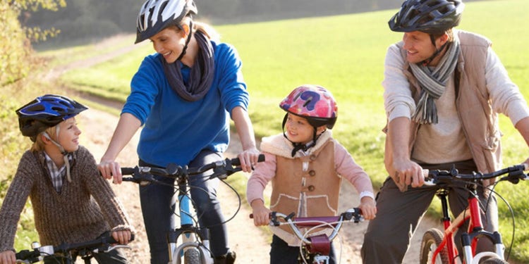 photo of two parents and children riding bikes on a dirt track